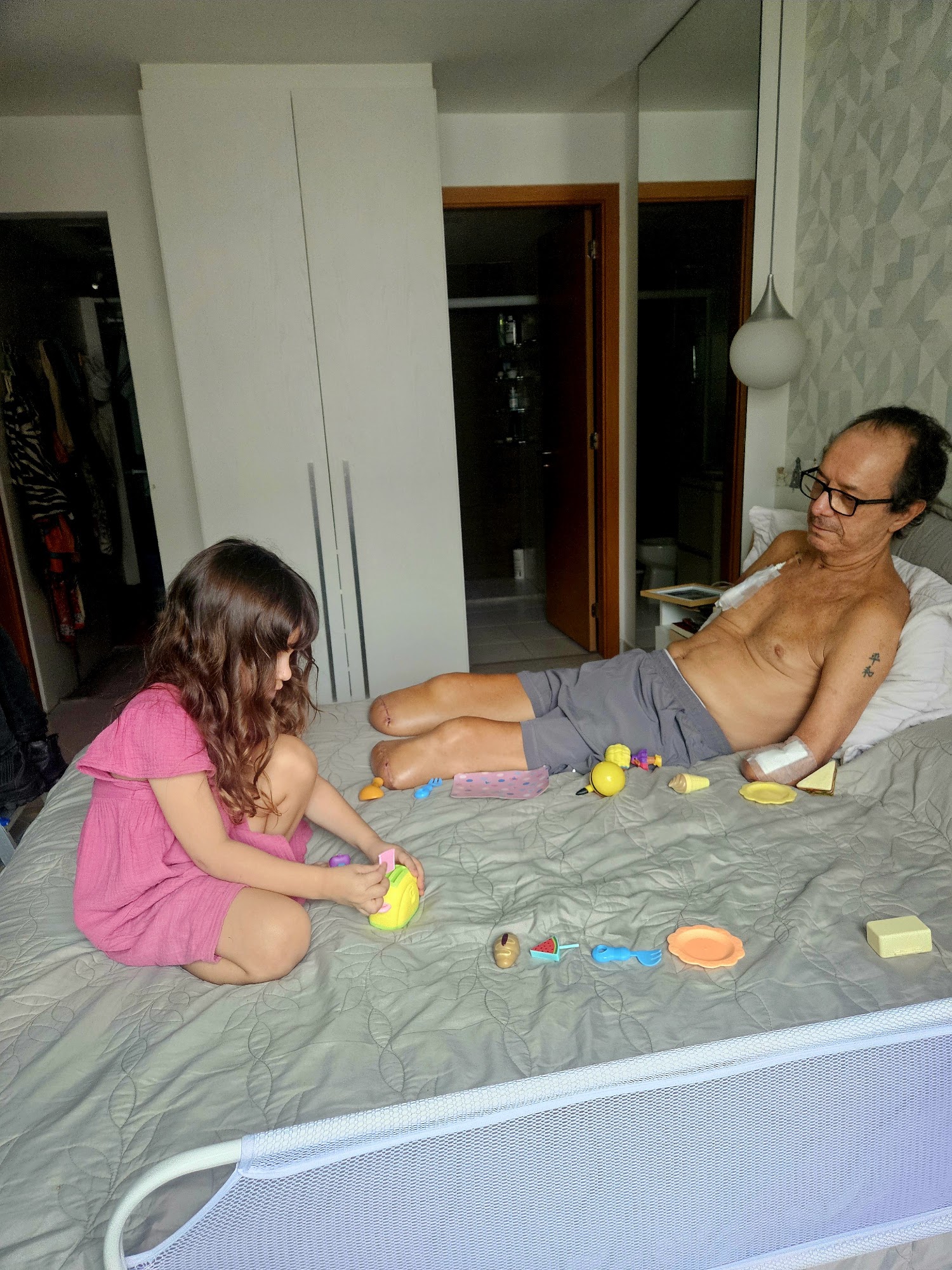 Flávio brincando com a neta sobre a cama